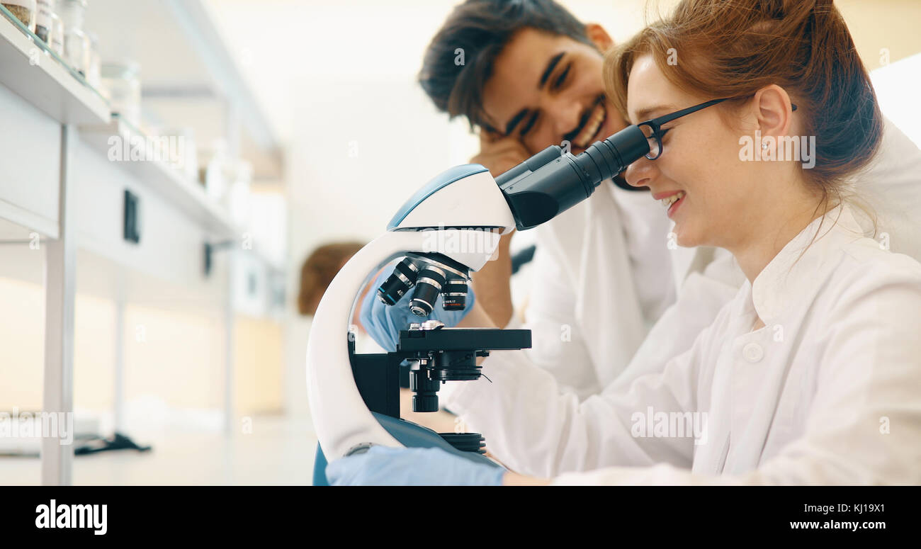 Gruppo di scienziati facendo ricerca guardando attraverso il microscopio Foto Stock