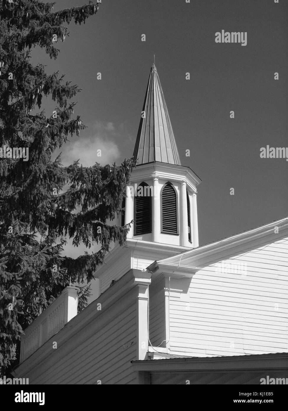 B&W vecchia chiesa e steeple contro il cielo chiaro. Foto Stock
