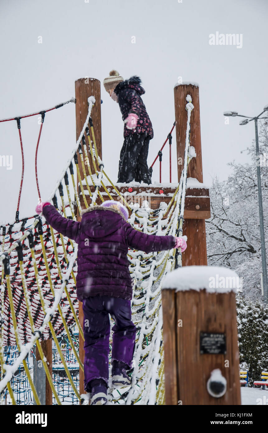 Due felici i bambini che giocano nel parco giochi invernale coperto di neve Foto Stock