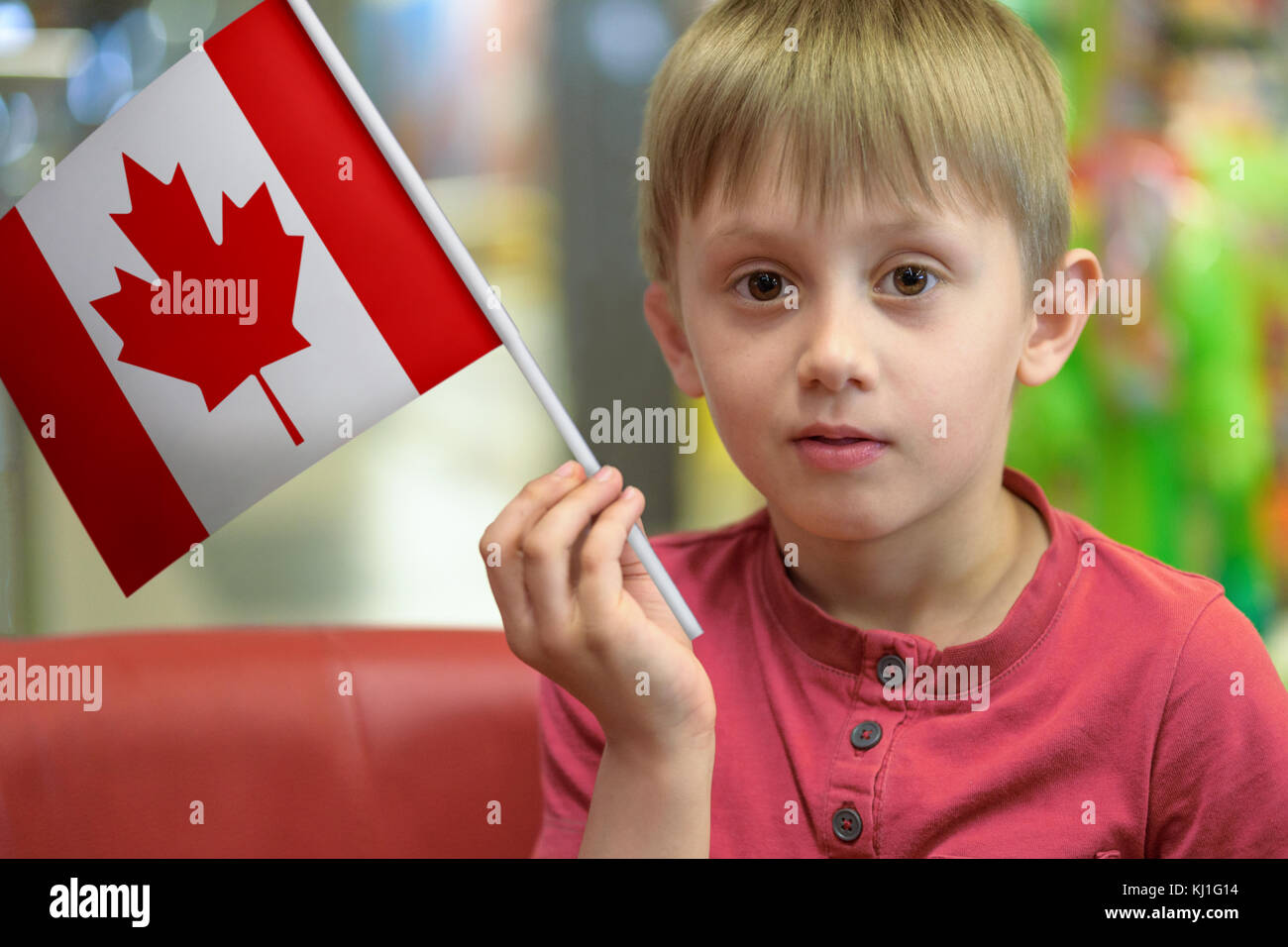 Immagine composita di un bambino come un patriota che tiene in mano una bandiera di carta del Canada Foto Stock