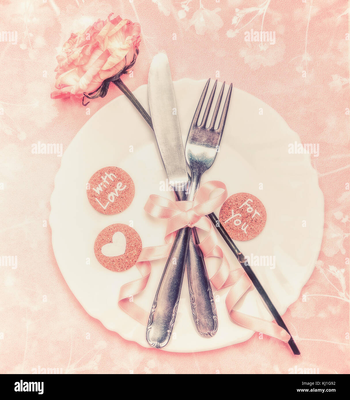 Tabella romantica impostazione con piastra, rose fiore, posate e nastro pastello su sfondo rosa, vista dall'alto Foto Stock