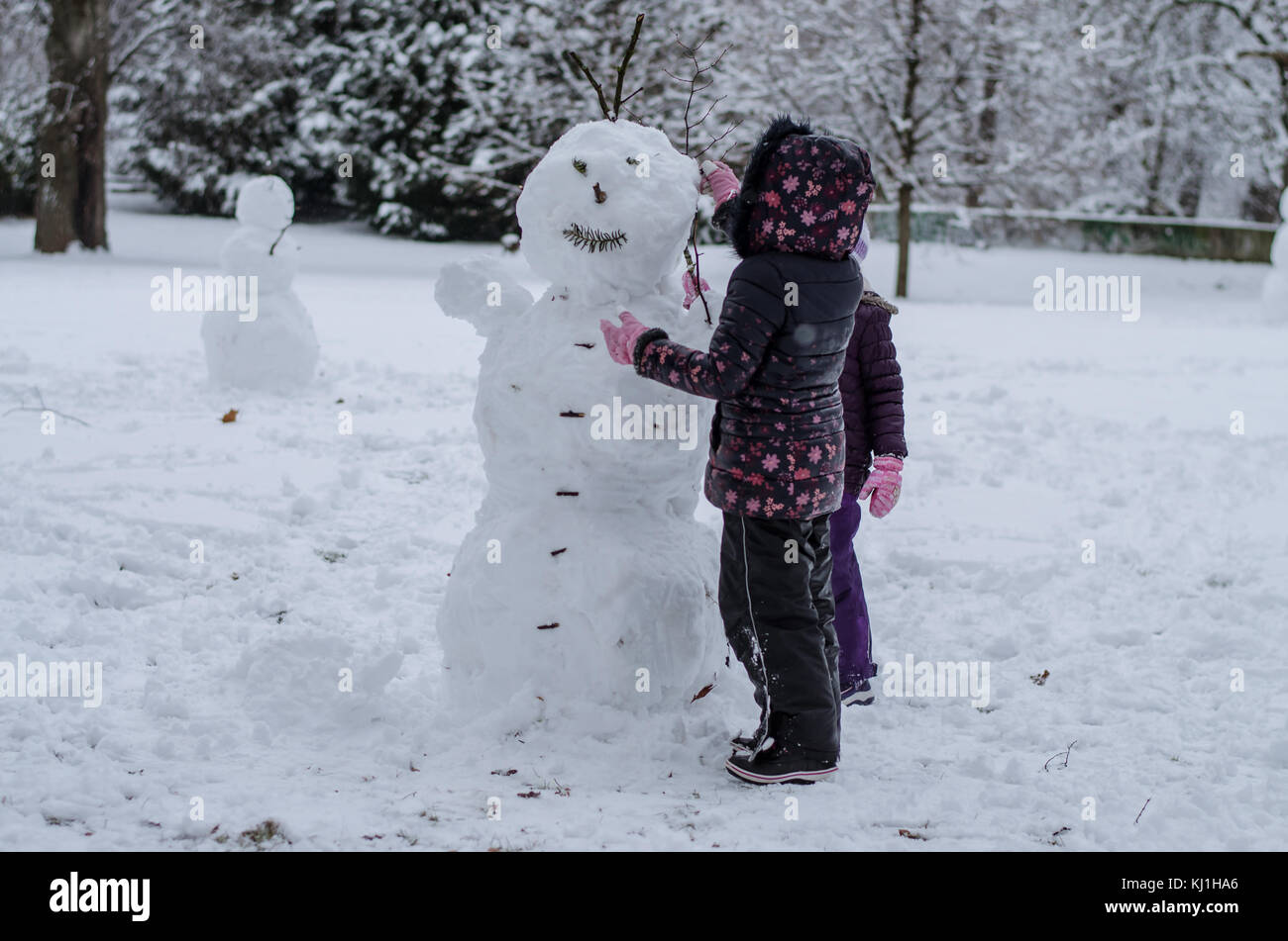 Dei bambini felici godendo di atmosfera invernale in parcheggio coperto da neve giocando e costruire un pupazzo di neve Foto Stock
