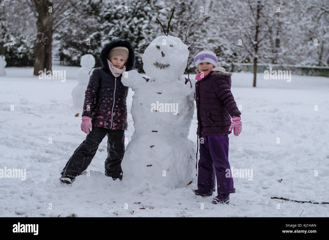 Due sorelle ragazze bambini giocare nel parco invernale mentre costruire un pupazzo di neve Foto Stock