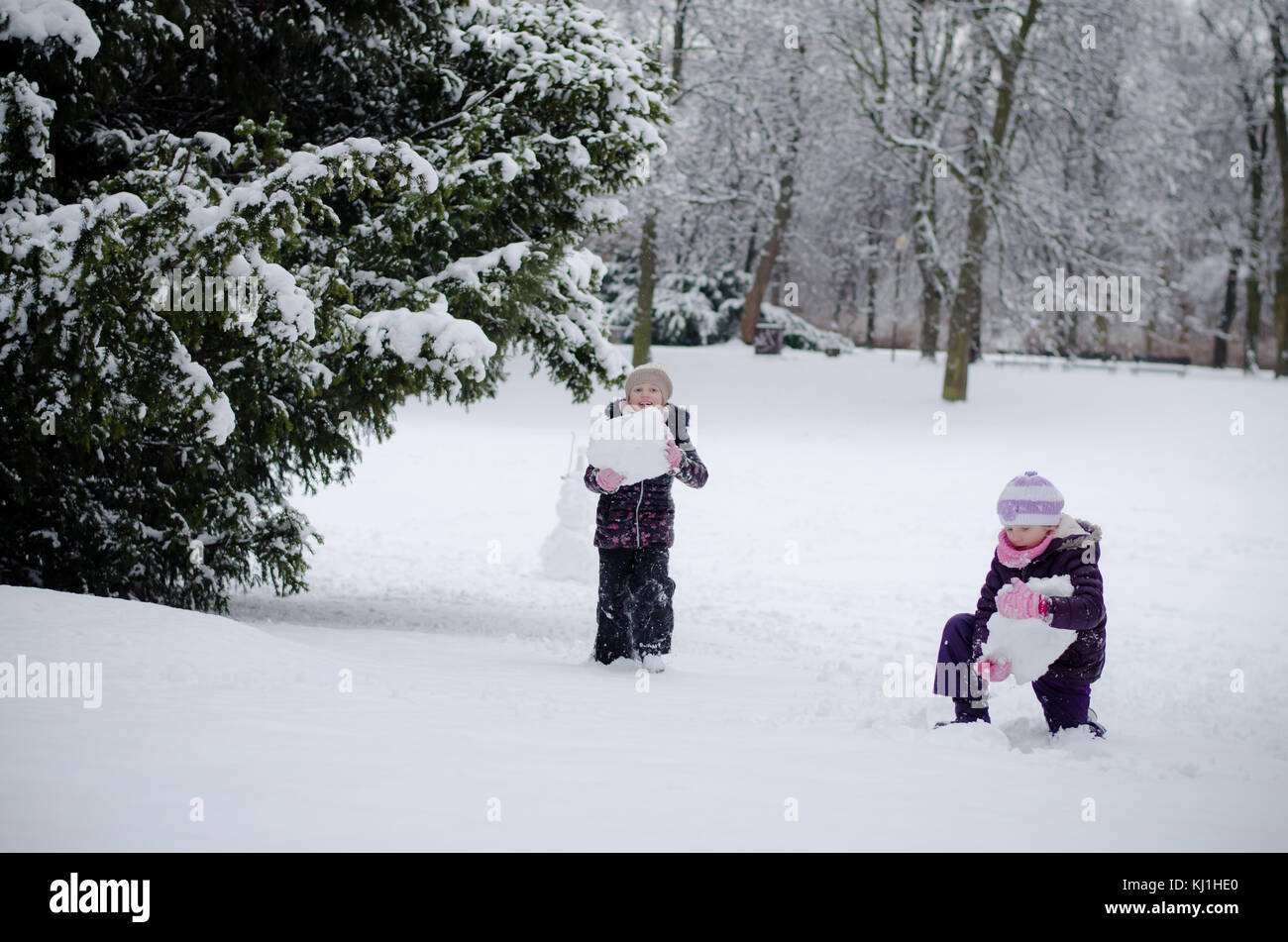 Due splendidi bambini ragazze sorelle giocando in winter park con le palle di neve Foto Stock