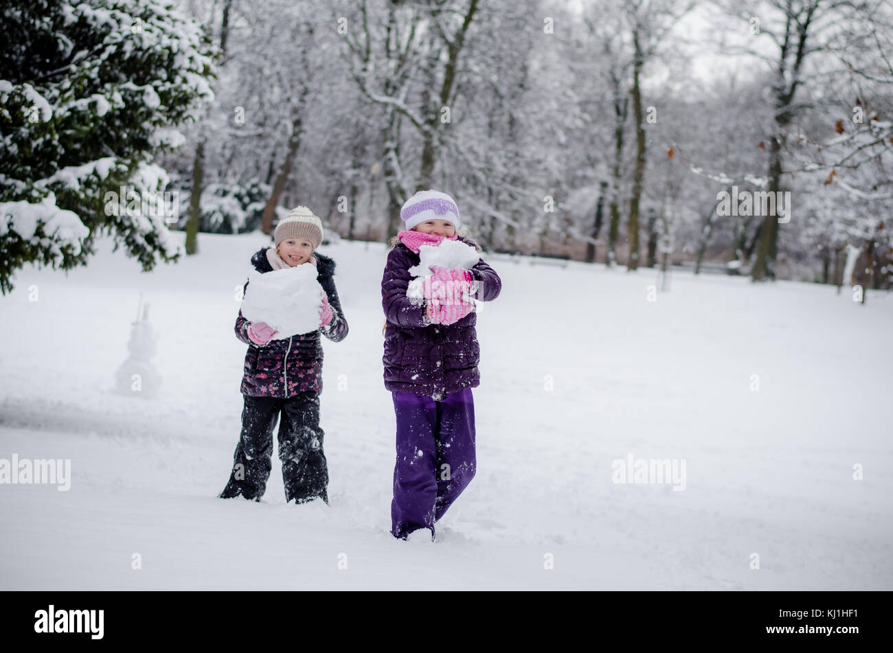 Due splendidi bambini ragazze sorelle giocando in winter park con le palle di neve Foto Stock