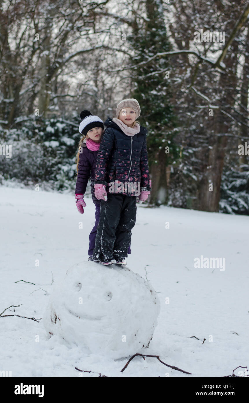 Due splendidi bambini chirls sorelle giocando in winter park mentre costruire un pupazzo di neve Foto Stock