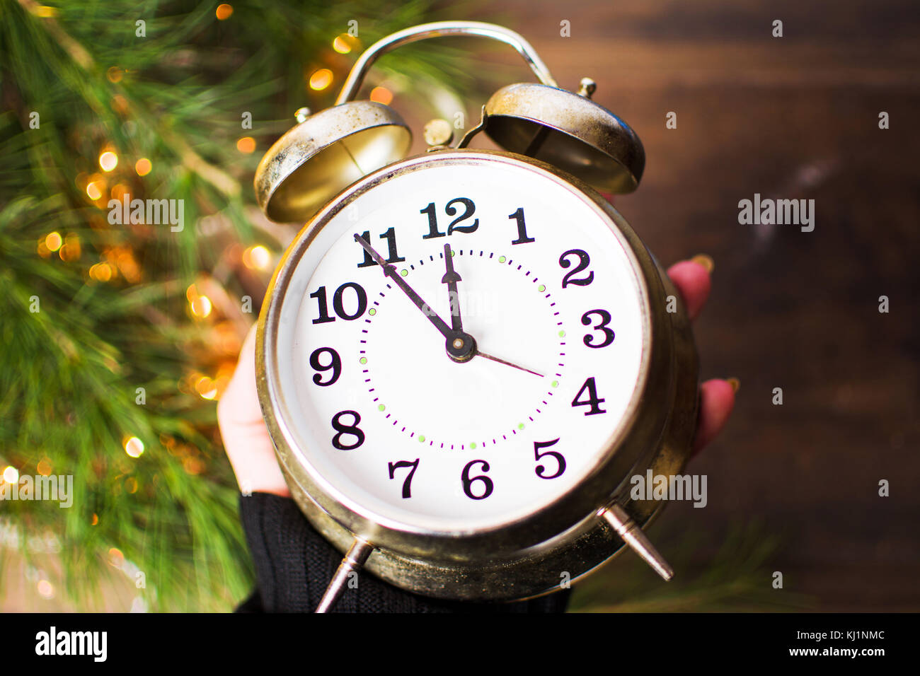 Mano azienda orologio vintage avvicina mezzanotte e la festa delle luci di Natale Foto Stock