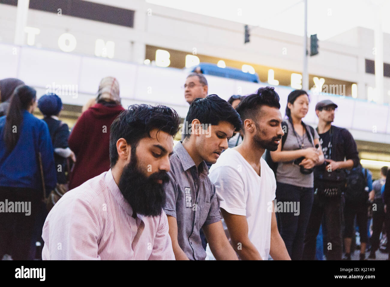 Manifestanti lotta contro Donald Trump musulmana del divieto di viaggio. Uomini pregando davanti a tom bradley international airport. Foto Stock