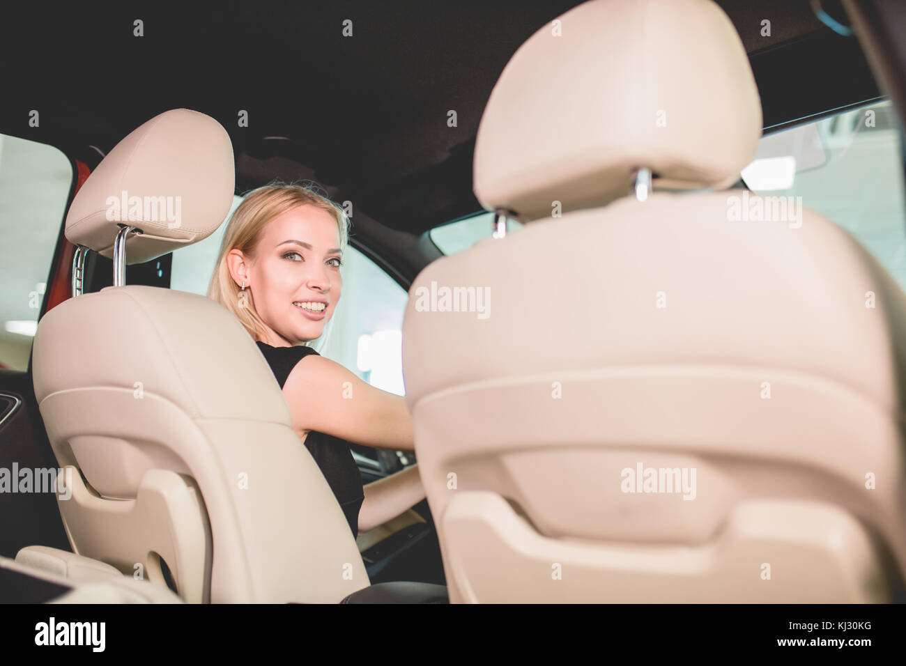 Donna graziosa sul sedile anteriore della nuova vettura in auto showroom. Foto Stock