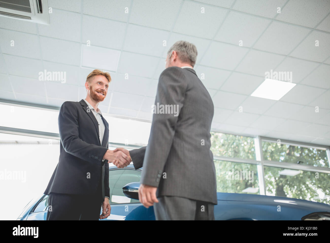 Uomo bello agitando la mano con il venditore del veicolo. Foto Stock