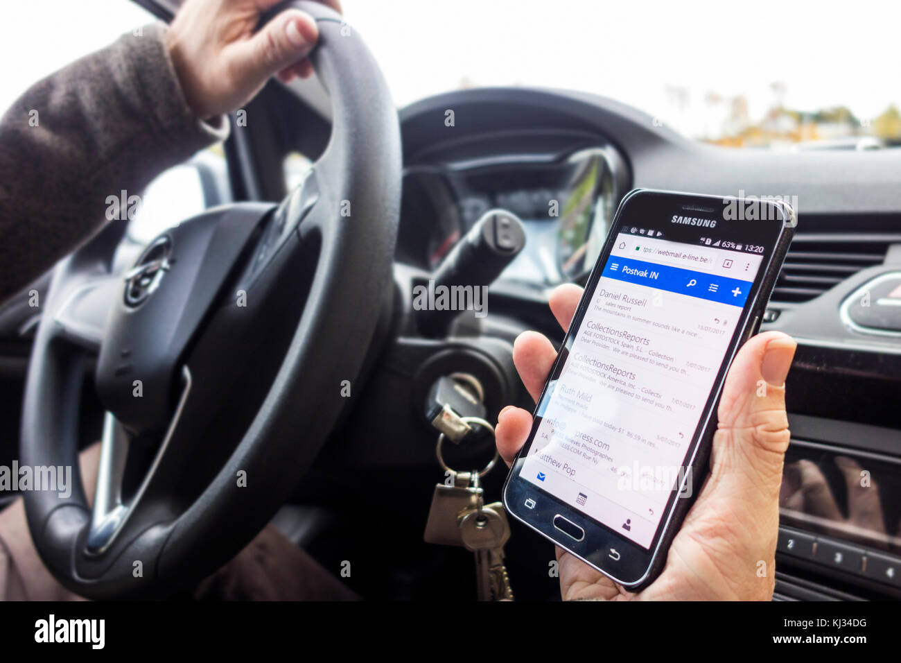 Irresponsabile uomo al volante dei messaggi di controllo sulla smart phone / smartphone / cellulare mentre si guida auto sulla strada Foto Stock