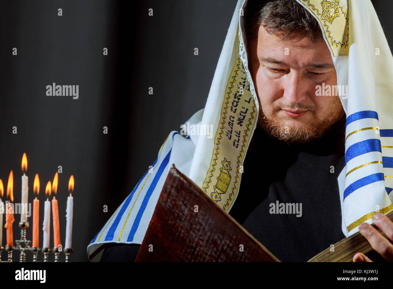 Candele di illuminazione a mano maschio in menorah sul tavolo Hanukkah Foto Stock