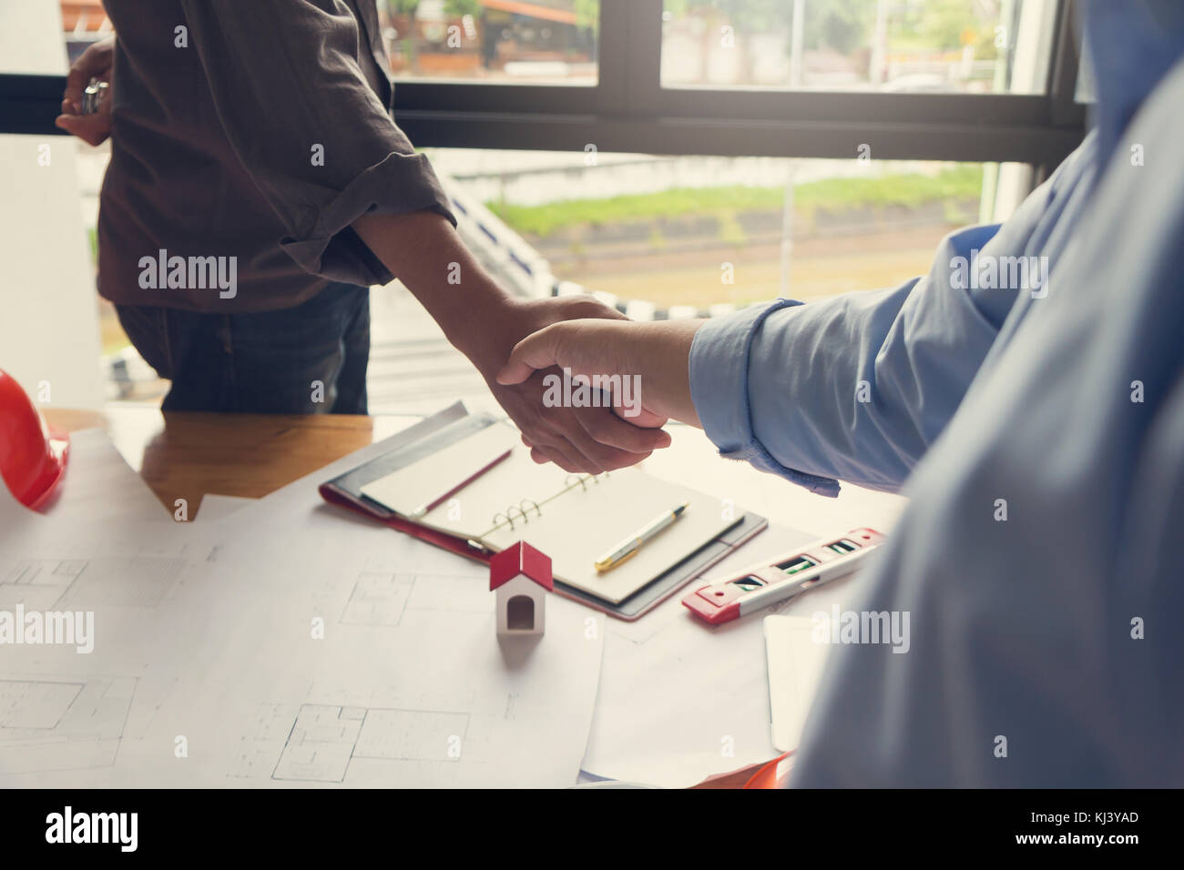 Ingegnere e architetto concetto, ingegnere architetti office team di lavoro agitando la mano con blueprint e modello di casa sulla scrivania in ufficio, effetto vintage Foto Stock