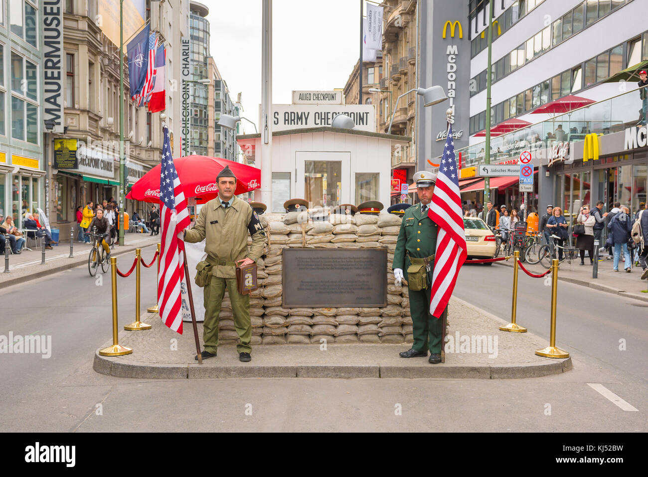 Il Checkpoint Charlie Berlino, due uomini che tengono bandierine americane, riprendendo i ruoli di guardie di attraversamento al Checkpoint Charlie di attrazione del turismo a Berlino Foto Stock
