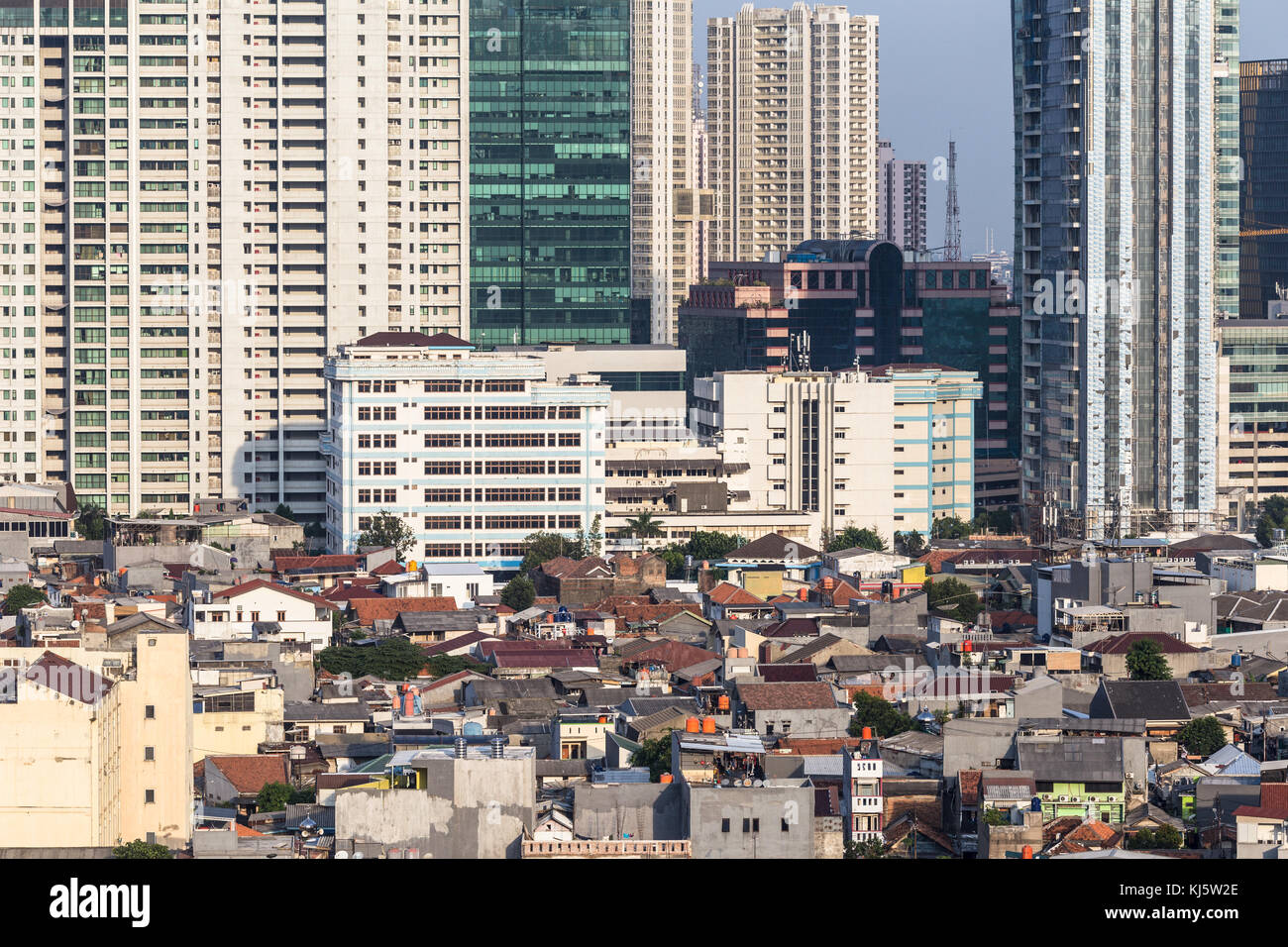 Vista aerea di un basso edificio residenziale, ancora organizzare come un villaggio in contrasto con le moderne torri di condominio nel cuore di Jakarta, indo Foto Stock
