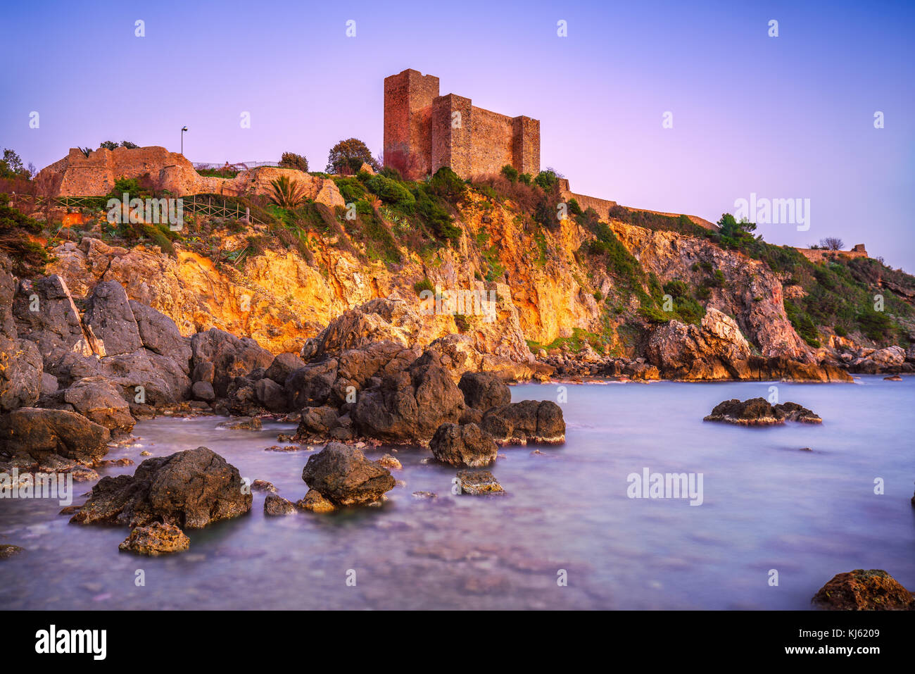 Talamone la spiaggia di roccia e fortezza medievale rocca aldobrandesca pareti e al tramonto. maremma argentario viaggi italiani di destinazione. toscana, italia. Foto Stock