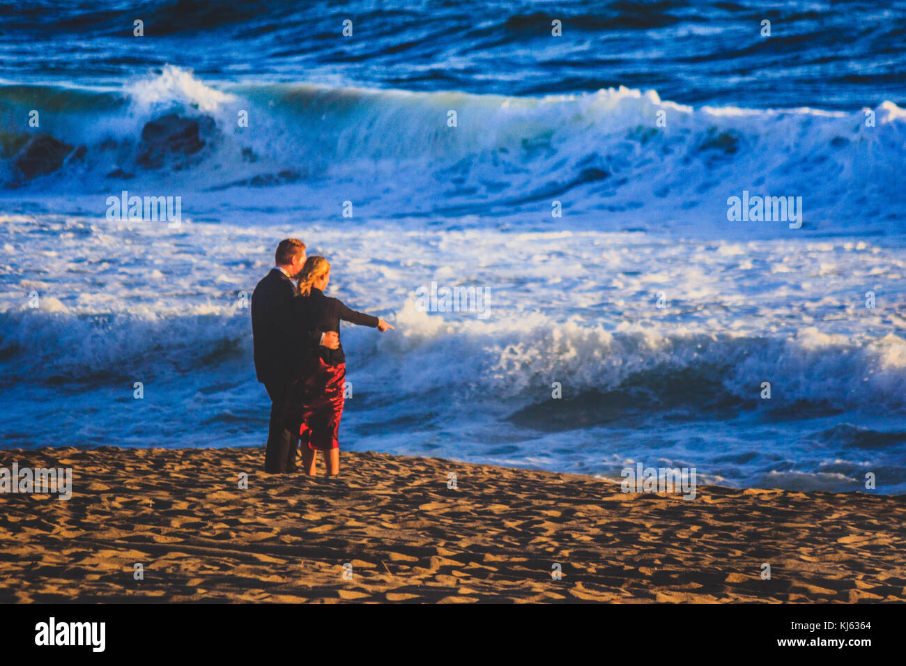 Coppia giovane vestito da sera a guardare il tramonto lungo Point Dume State Beach Foto Stock