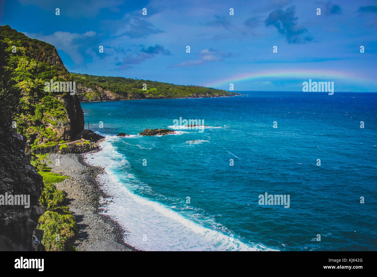 Onde che si infrangono a Maui spiaggia con un arcobaleno di distanza sulla strada di Maui, Hawaii Foto Stock