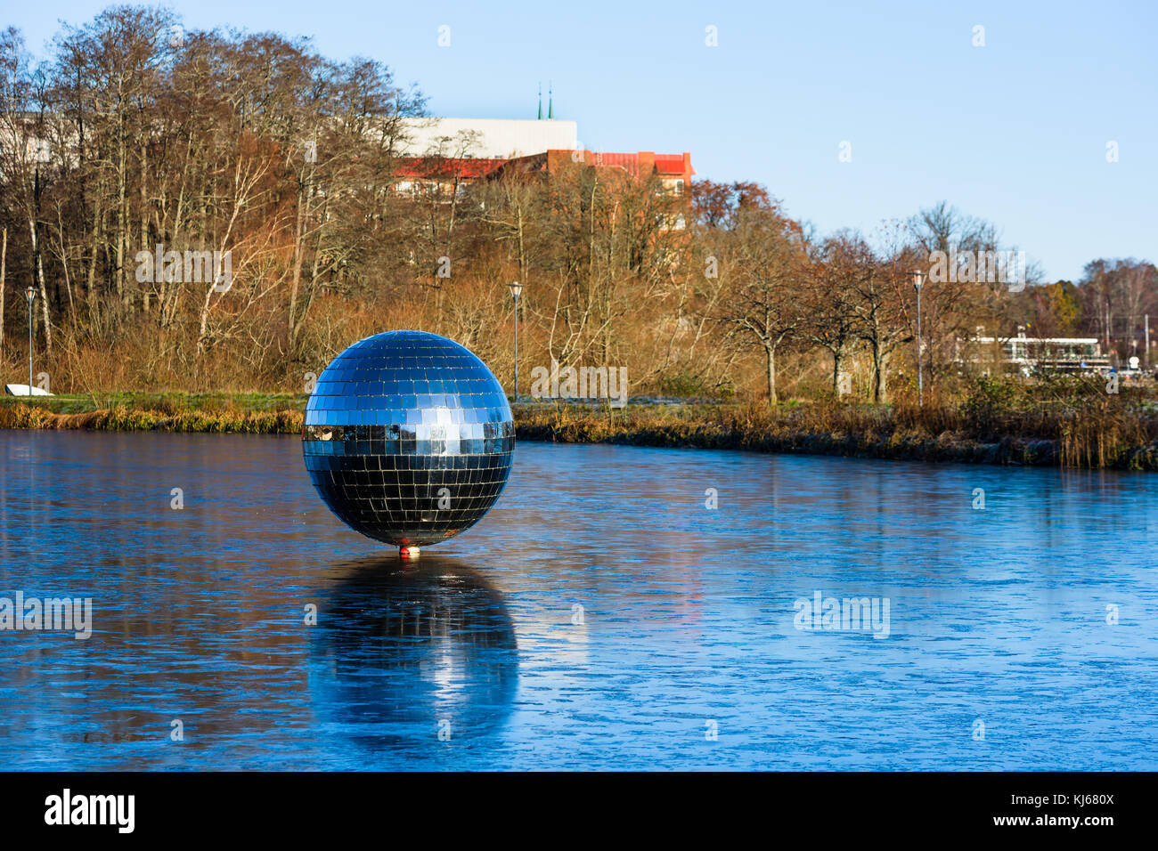 Vaxjo, Svezia - 13 novembre 2017: documentario della vita quotidiana e l'ambiente. rotante gigantesca palla da discoteca sul lago vaxjo con ghiaccio sottile che ricopre il Foto Stock