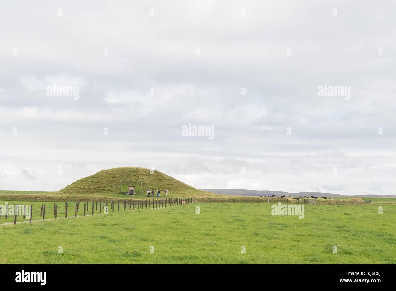 Il gruppo del tour si trova fuori dal Maeshowe Neolitico Chambered Cairn, parte del cuore del sito del Neolitico Orkney, patrimonio dell'umanità, Orkney, Scozia, Regno Unito Foto Stock