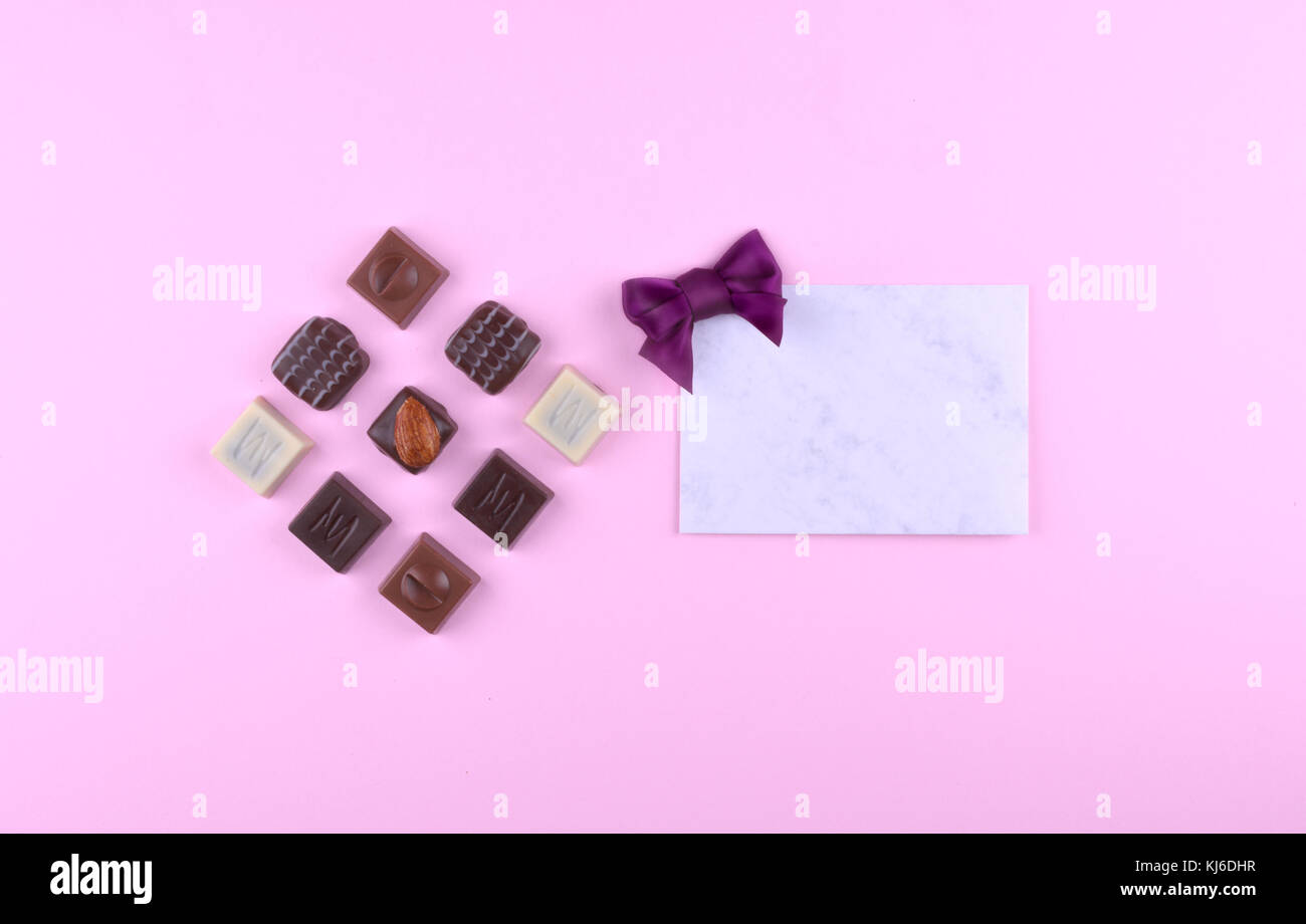 Raccolta di deliziose praline di cioccolato sulla tendenza rosa sfondo. Piatto stile laici. luogo per il vostro testo. Foto Stock