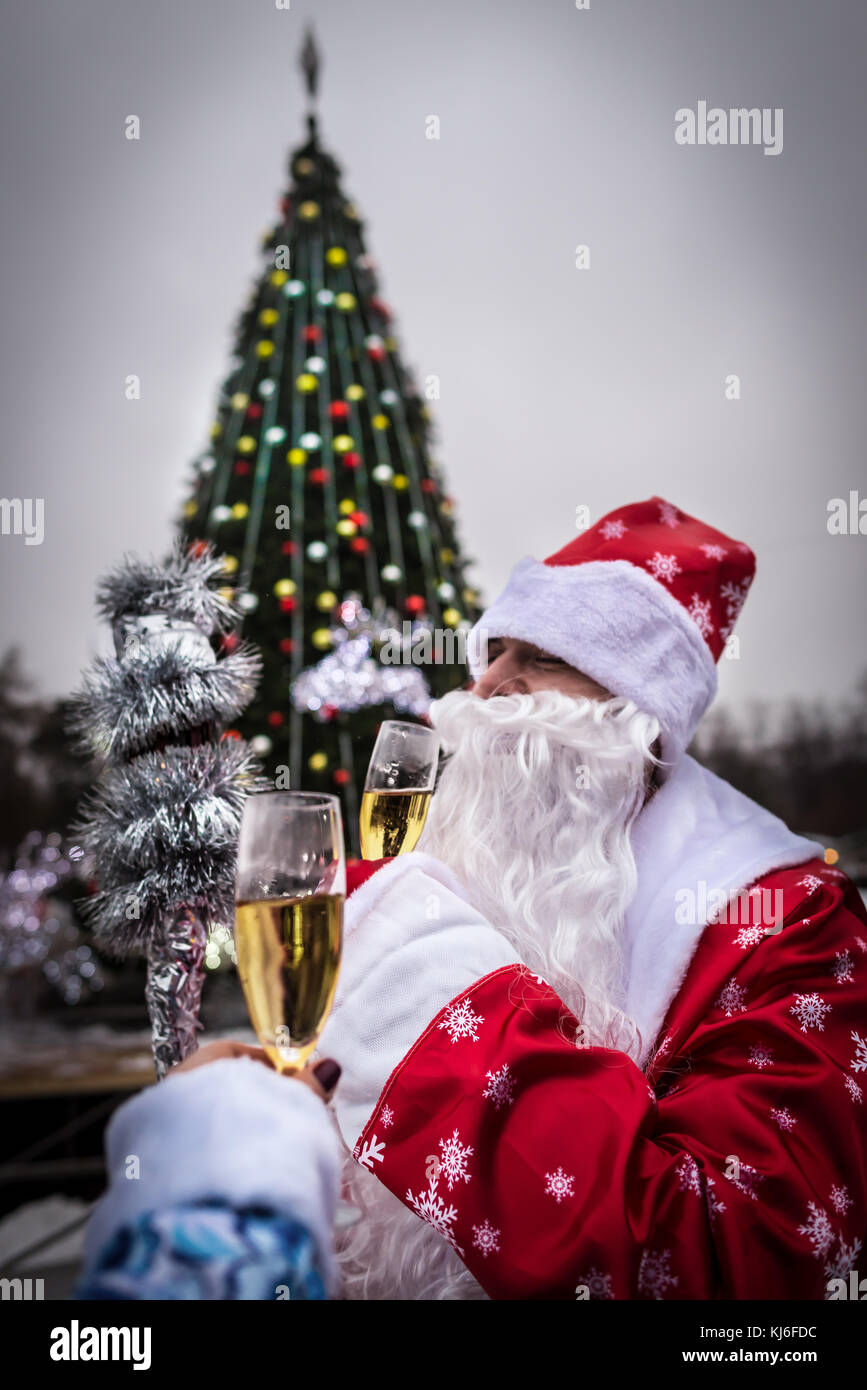 Celebrazione e anno nuovo concetto. l uomo con la barba detiene il vetro di champagne. guy vicino albero di natale nel parco santa claus in Red Hat. Felice anno nuovo! Foto Stock