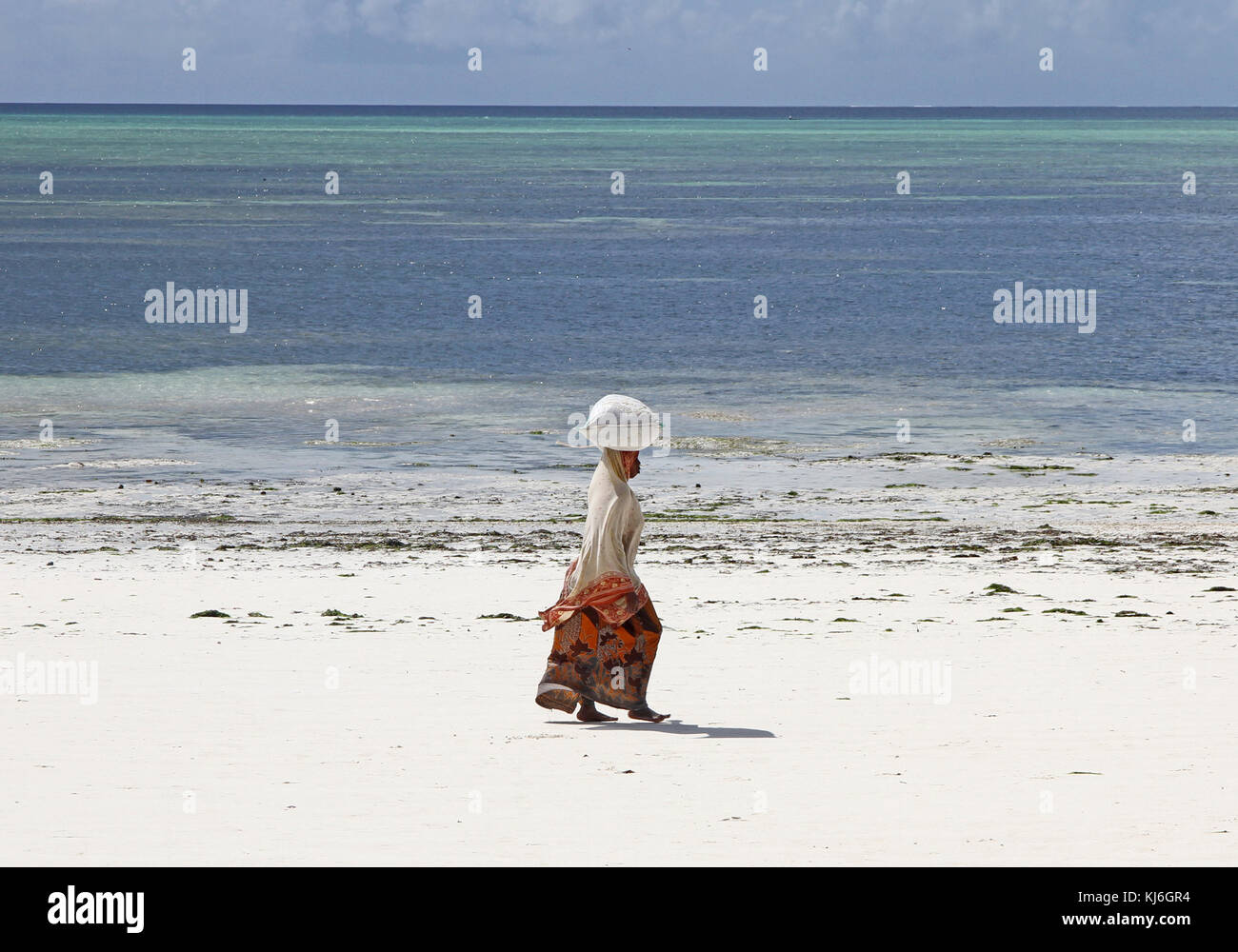 Donna che cammina sulla spiaggia, isola di Unguja, Zanzibar, Tanzania Foto Stock