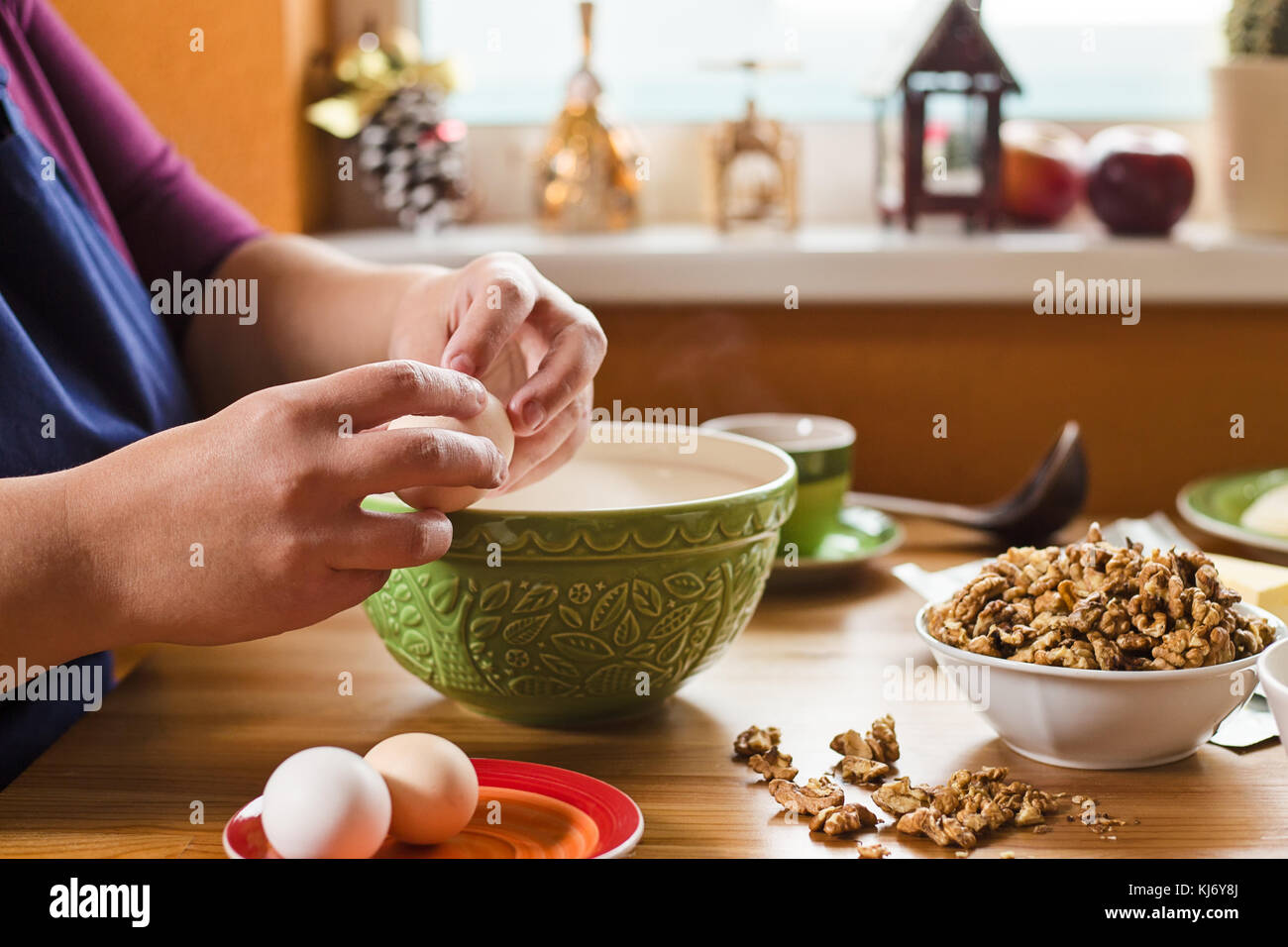 Close up foto di giovani mani femminili rompendo un uovo dal bordo della  tazza verde, vaschetta piena di wallnuts è posto vicino e ingredienti per  baki Foto stock - Alamy