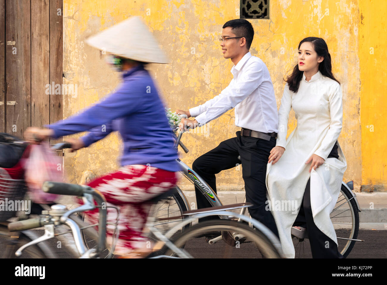I giovani Sposi su una bicicletta nel Patrimonio Mondiale dell'Unesco Centro di storia di Hoi An, Vietnam Foto Stock