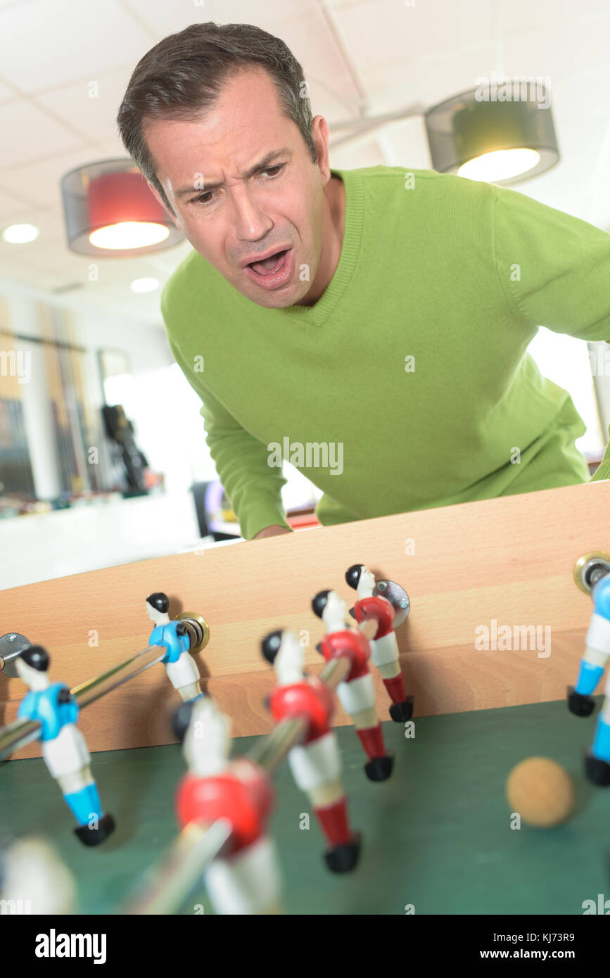 Uomo eccitato giocare calcio balilla Foto Stock