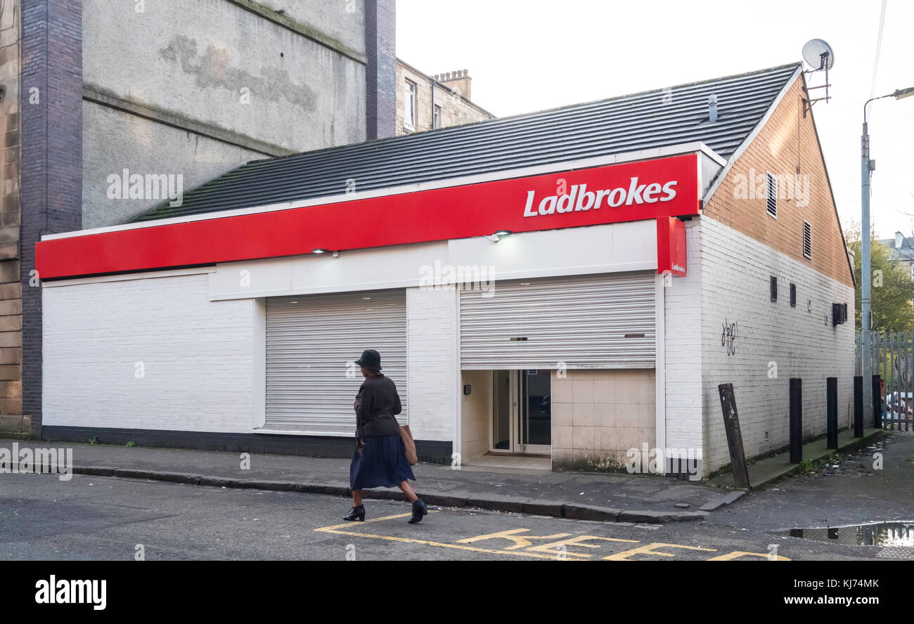 Austere Ladbrokes scommettere negozio nel distretto di Govanhill di Glasgow, Scozia, Regno Unito Foto Stock