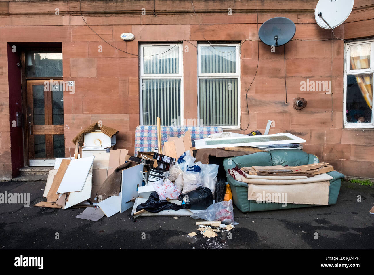 Spazzatura accatastata sulla strada al di fuori dell'edificio inquilino nel quartiere Govanhill di Glasgow, Scozia, Regno Unito Foto Stock