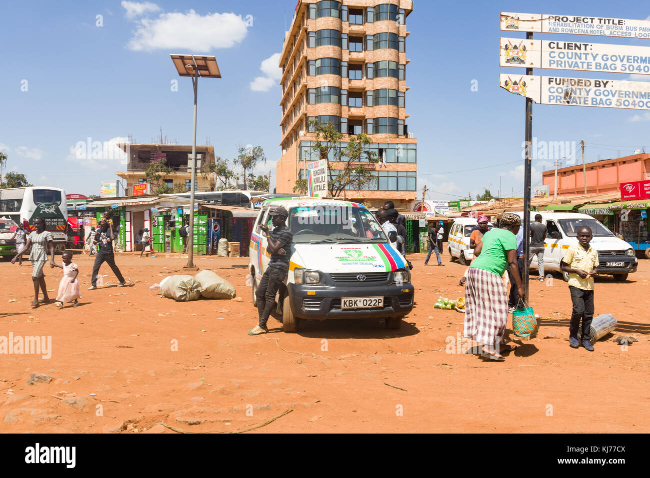 .Un uomo africano sorge da un piccolo minibus nel mezzo di una città con la gente camminare passato, Uganda, Africa orientale Foto Stock