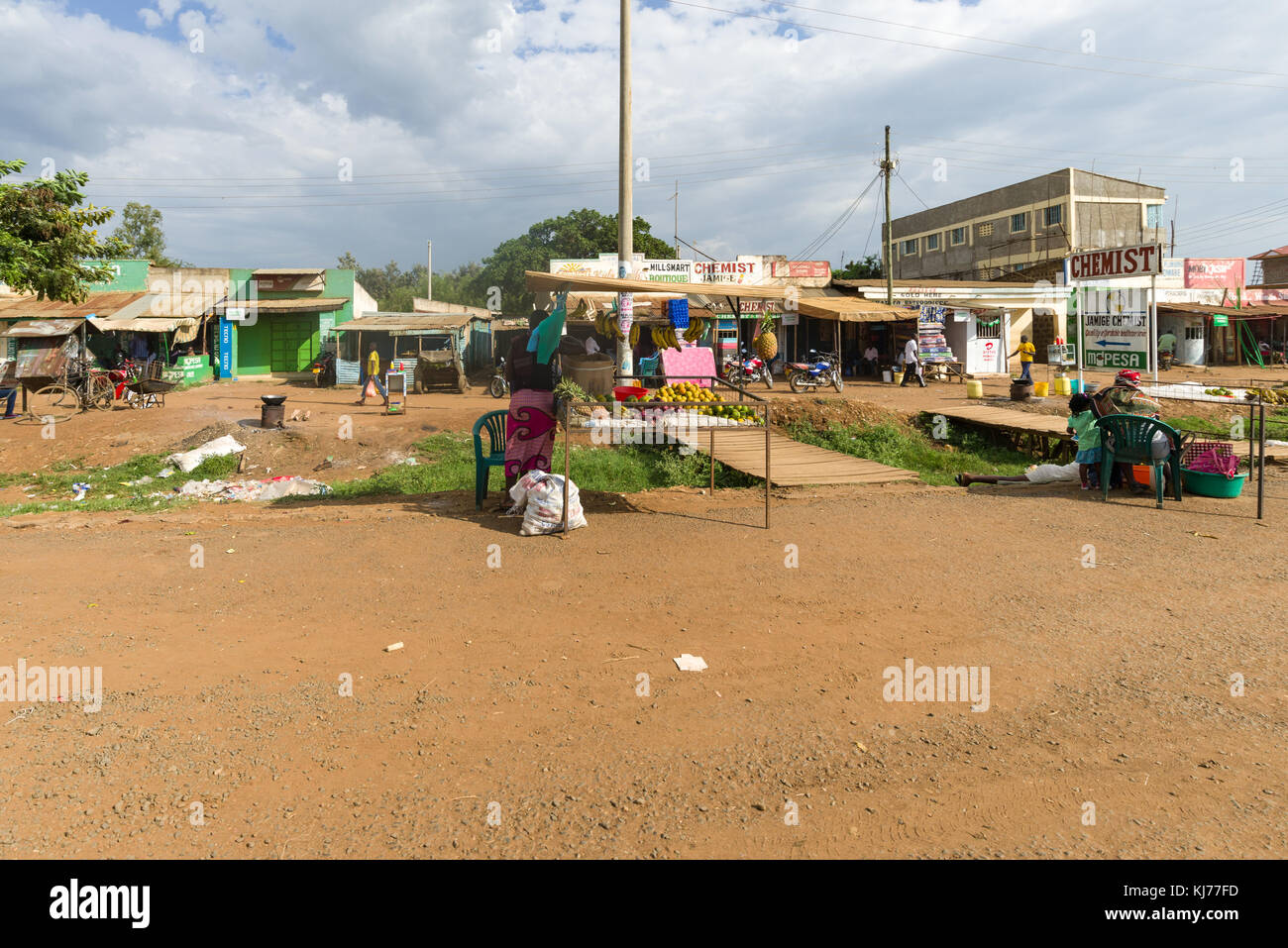 Una donna africana si distingue per la sua piccola stalla stradale per la vendita di frutta e verdura in una piccola città, Kenya, Africa orientale Foto Stock