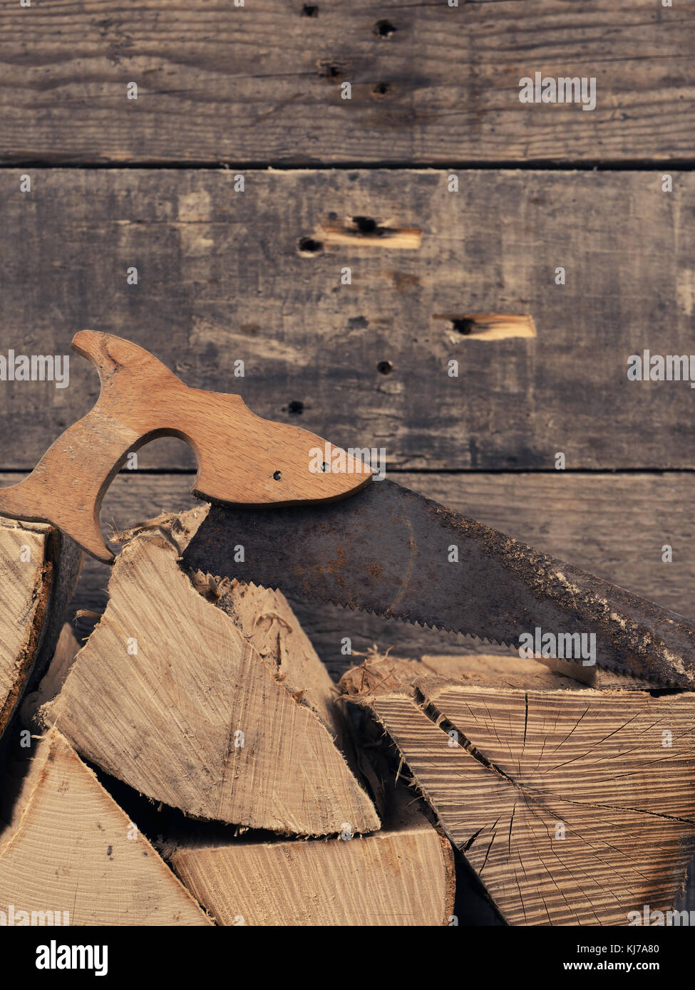 Pila di faggio legna con un vecchio e rusty sega, spazio per il testo sulla parete in legno Foto Stock