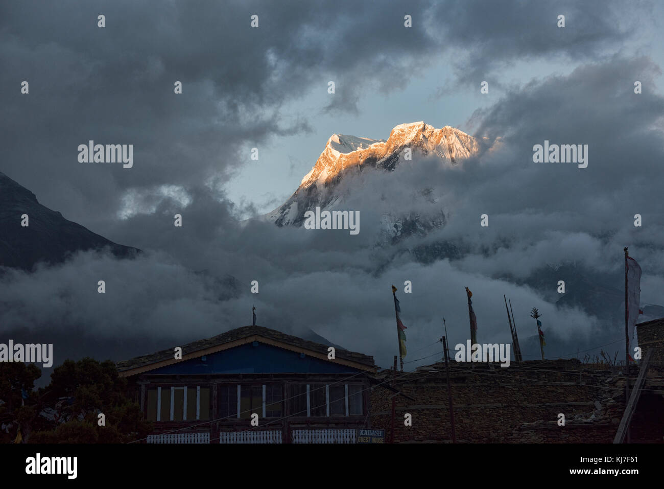 Annapurna iii visto attraverso le nuvole di sunrise, con ngawal borgo sottostante, circuito di Annapurna, Nepal Foto Stock