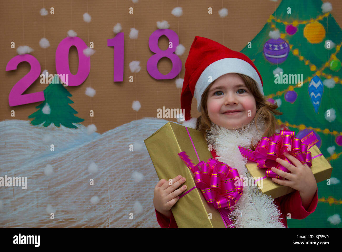 2018 felice anno nuovo. poco carino ragazza con un regalo. Sullo sfondo di un dipinto di albero di Natale e neve Foto Stock