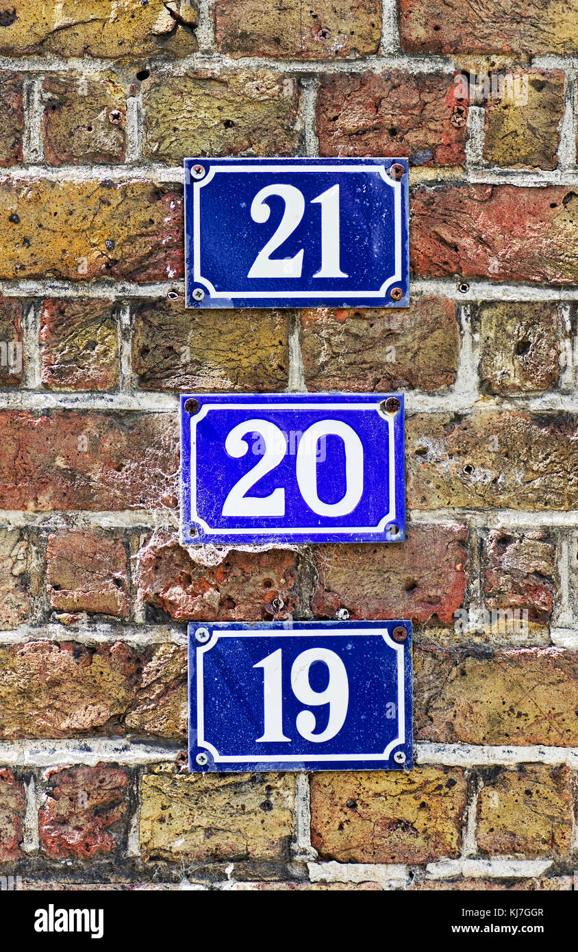 Numerico placche blu che mostra i numeri di diciannove, venti e twentyone contro un muro di mattoni. Foto Stock