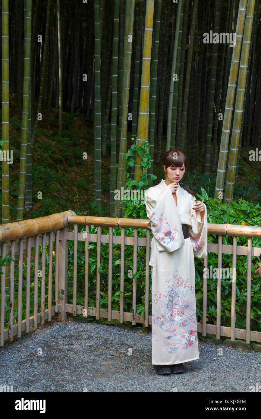 Giapponese giovane donna in kimono, di fronte a una foresta di bamboo a Kyoto, Giappone Foto Stock