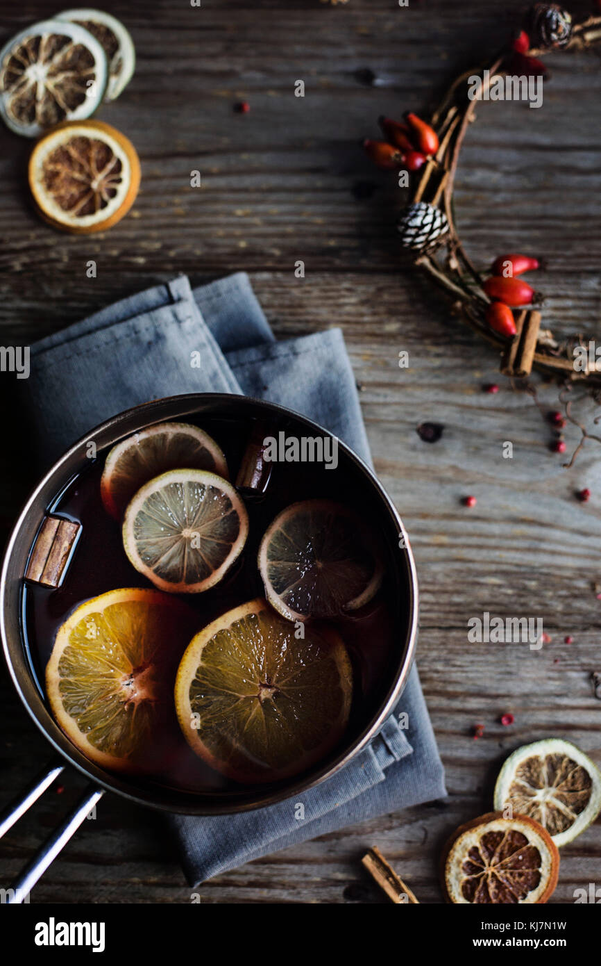 Inverno caldo bere. Vin brulé con arancia e limone e spezie in una casseruola su legno tavolo rustico. Atmosfera natalizia Foto Stock