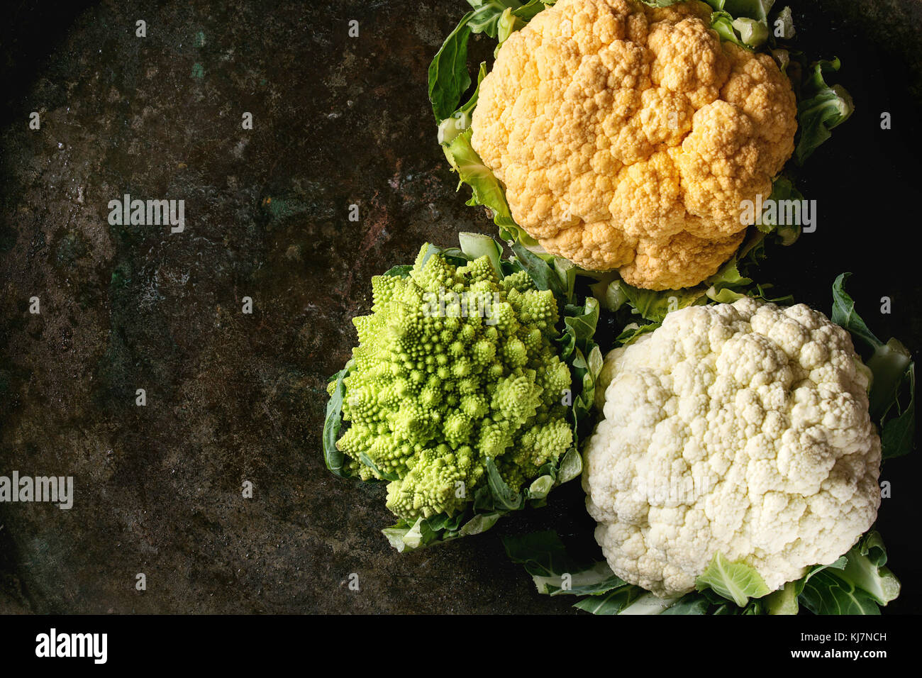 Varietà di crudo fresco colorato organico il cavolfiore e il cavolo Broccolo romanesco su texture scuro dello sfondo. Vista da sopra con lo spazio. Mangiare sano concetto Foto Stock