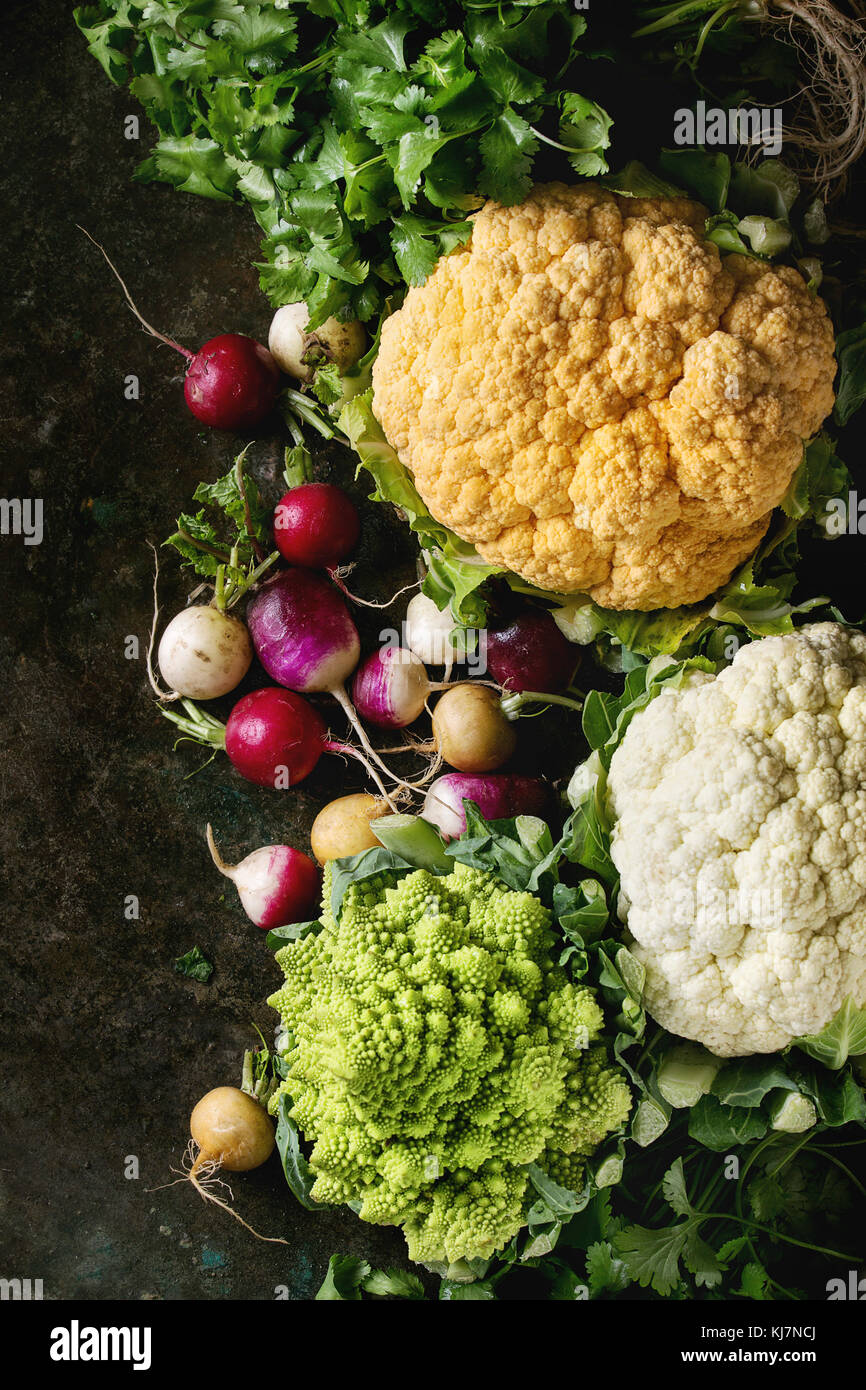 Varietà di carni di materie organiche cavolfiore colorati, cavolo Broccolo romanesco e radicchio con fascio di coriandolo su texture scuro dello sfondo. Vista da sopra con s Foto Stock