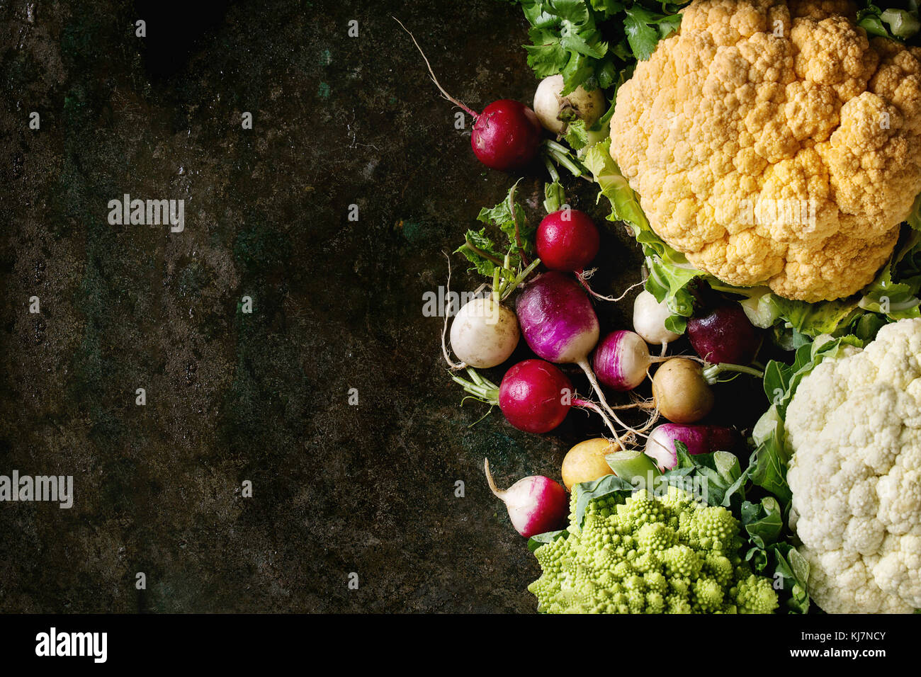 Varietà di carni di materie organiche cavolfiore colorati, cavolo Broccolo romanesco e radicchio con fascio di coriandolo su texture scuro dello sfondo. Vista da sopra con s Foto Stock