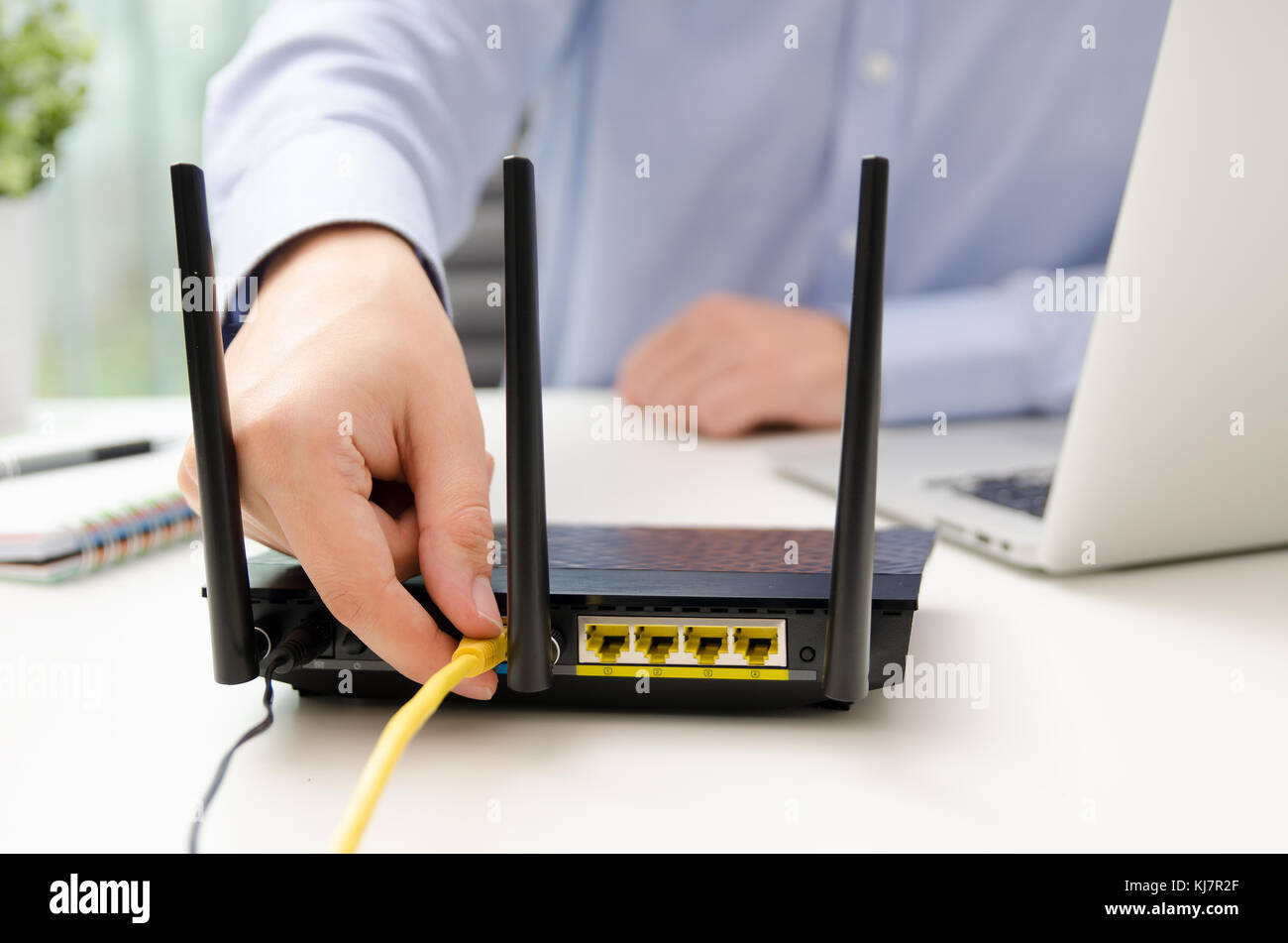 L'uomo tappi cavo Ethernet nel router. Il router wireless a banda larga di filo home office connettore maschio per cavo concept Foto Stock