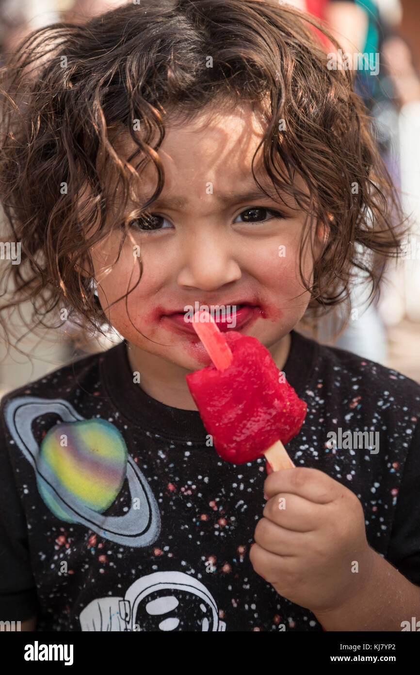 Nogales, Sonora Messico - Un bambino mangia un papavero rosso. Foto Stock