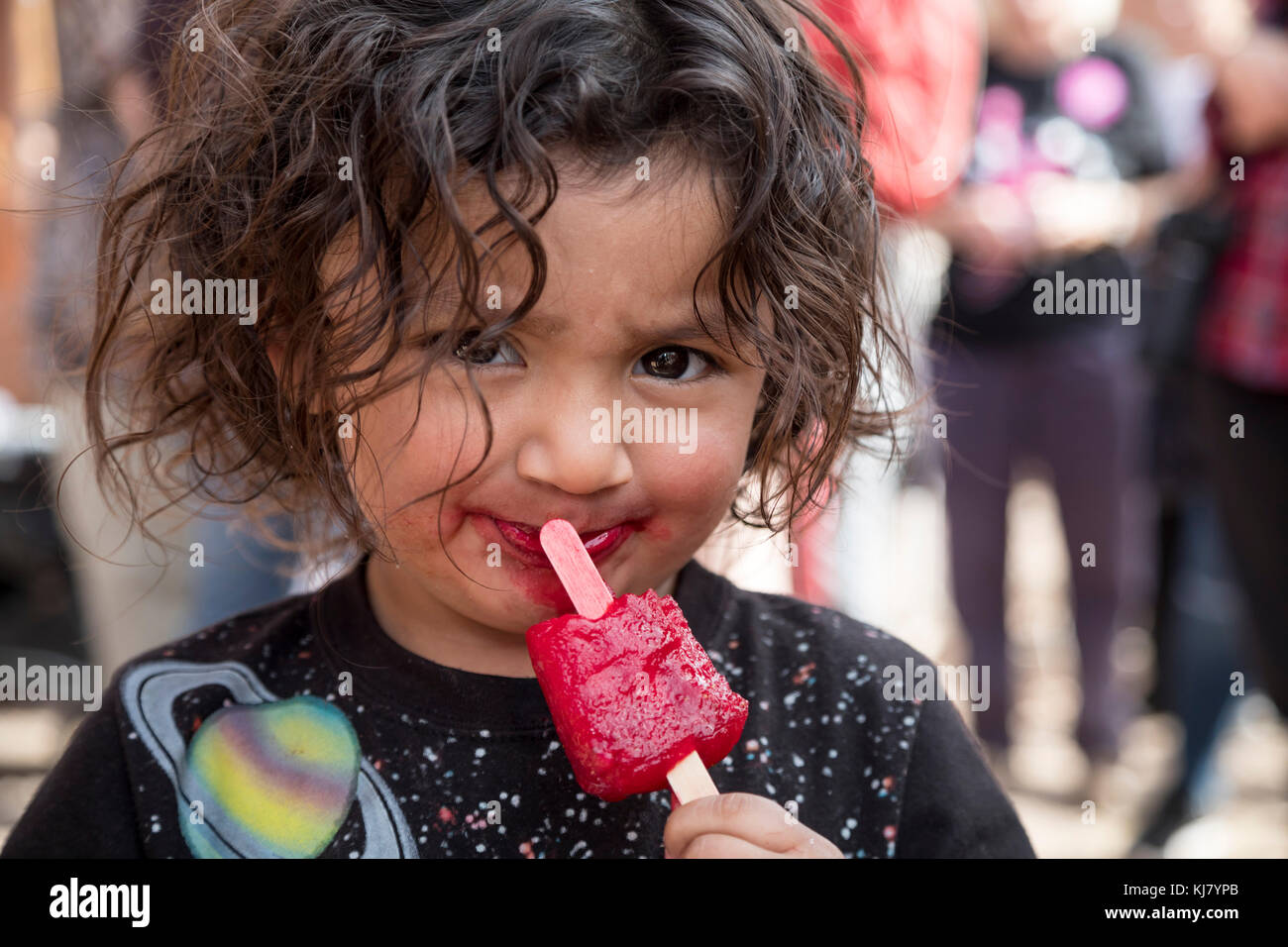 Nogales, Sonora Messico - Un bambino mangia un papavero rosso. Foto Stock
