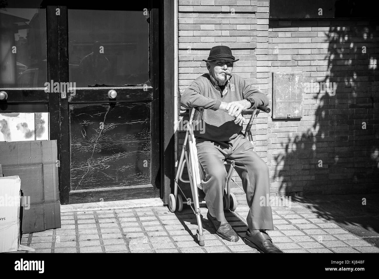 Un vecchio uomo da Siviglia seduto su una sedia e fumare il suo sigaro, Sevilla, Sevilla - Spagna. Foto Stock