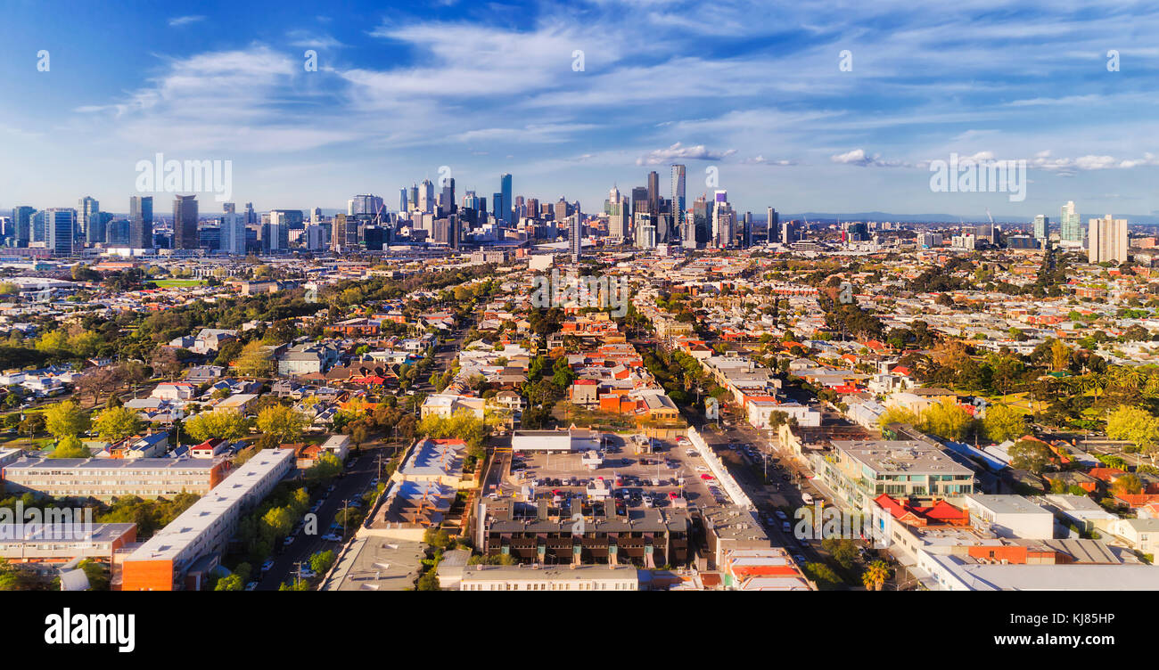 Vista aerea della città di Melbourne CBD alti torri dal porto di Melbourne e Southbank sopra sobborgo residenziale tetti delle case e strade locali, strade, ca Foto Stock