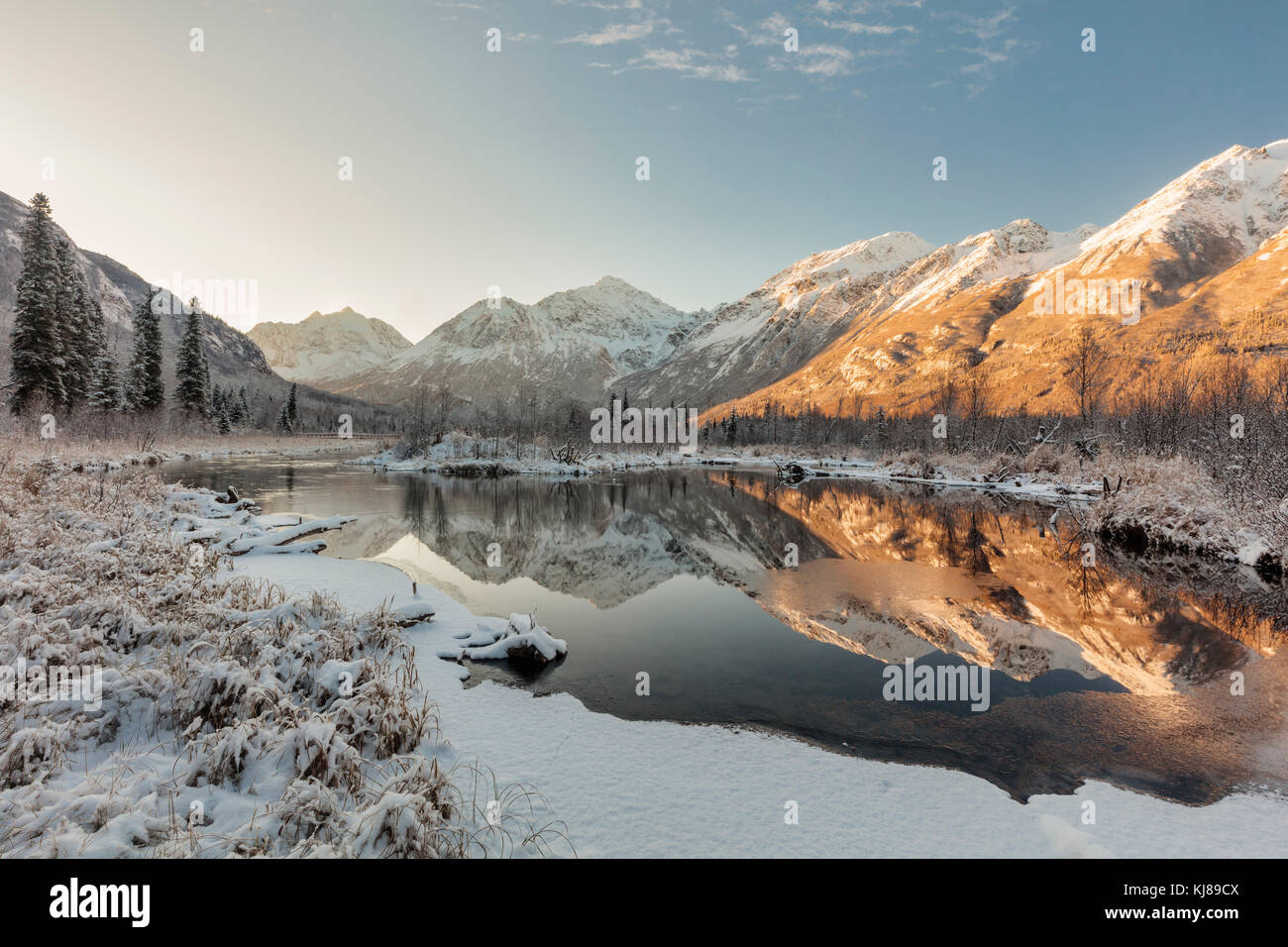 La luce dell'alba illumina la prima neve della stagione mentre ricopre la Eagle River Valley e le Chugach Mountains nell'Alaska centro-meridionale. Foto Stock