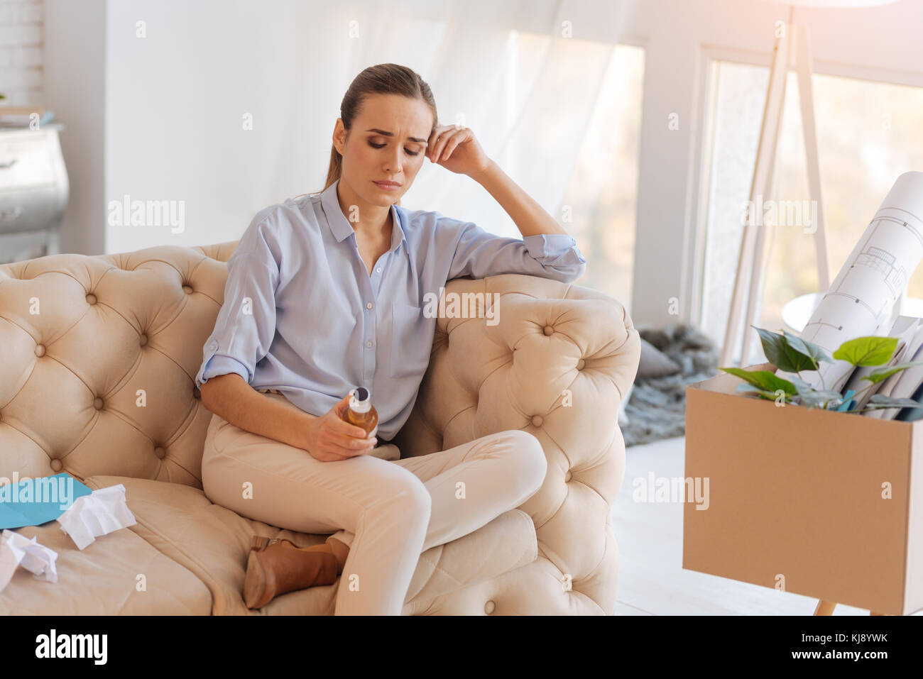 Disoccupati triste donna seduta con una bottiglia di alcool Foto Stock